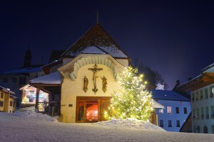 Beautifully decorated and illuminated Christmas fir tree in front of the church in Gruyere, Switzerland