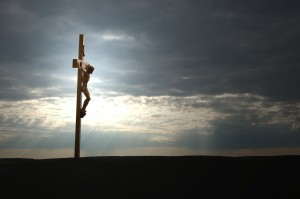 Jesus on the crucifix aganist a dark and dramatic sunset sky. Copy space