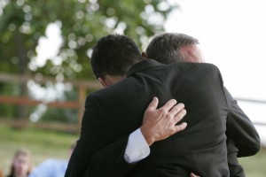 Two men hug each other.  Horizontal with copy space.