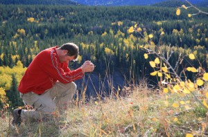 A man prays in a beautiful outdoor scene.