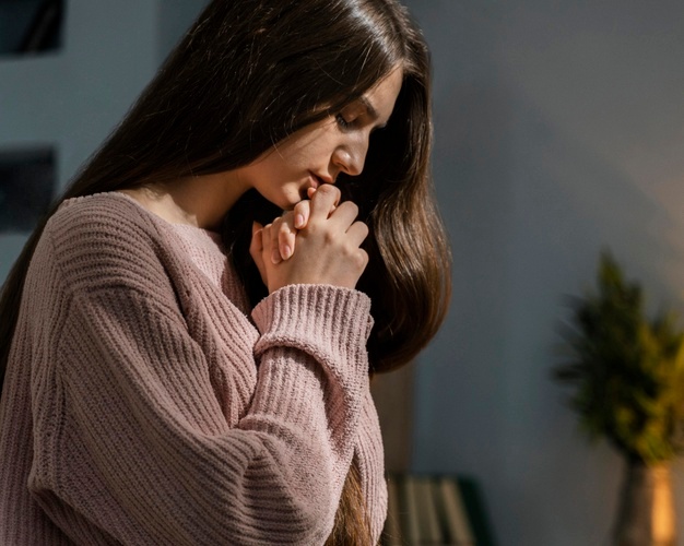 vista lateral de mulher orando buscando a vocação sacerdotal