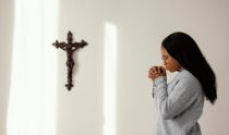 mulher religiosa rezando o terço em casa
